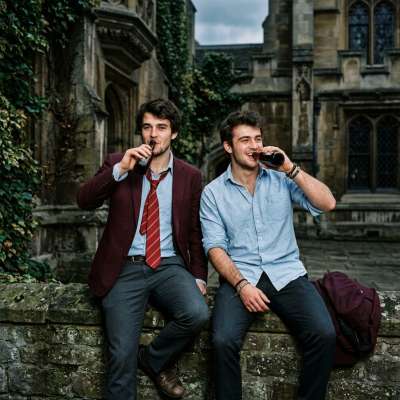Two scholars share a clandestine toast beneath the ivy, where ancient stones whisper secrets and rules fade into the...